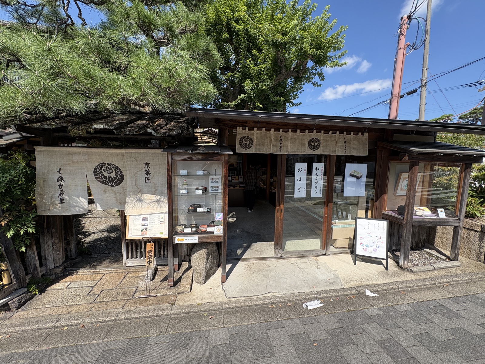 2026-09-22 ホテル近くの和菓子店「京菓匠 七條甘春堂」の外観。麻ののれんと「和モンブラン」「おはぎ」の貼り紙